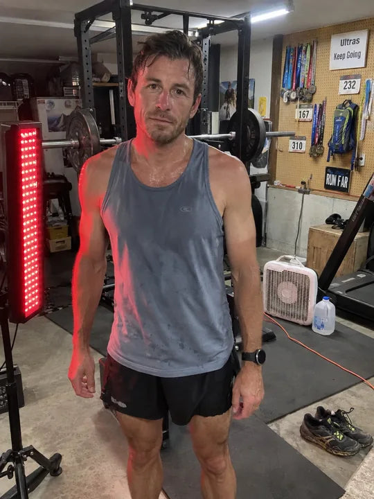 A man in a home gym beside a red-light panel