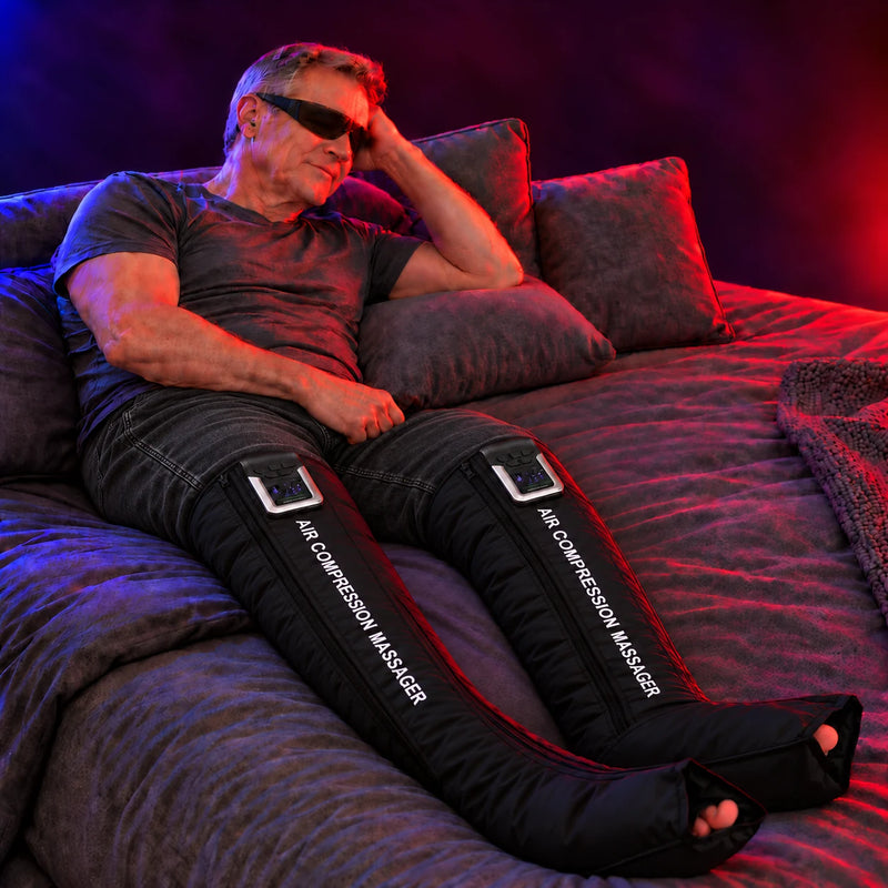 Man relaxing in bed wearing DrAcher AirStride Elite air compression recovery boots